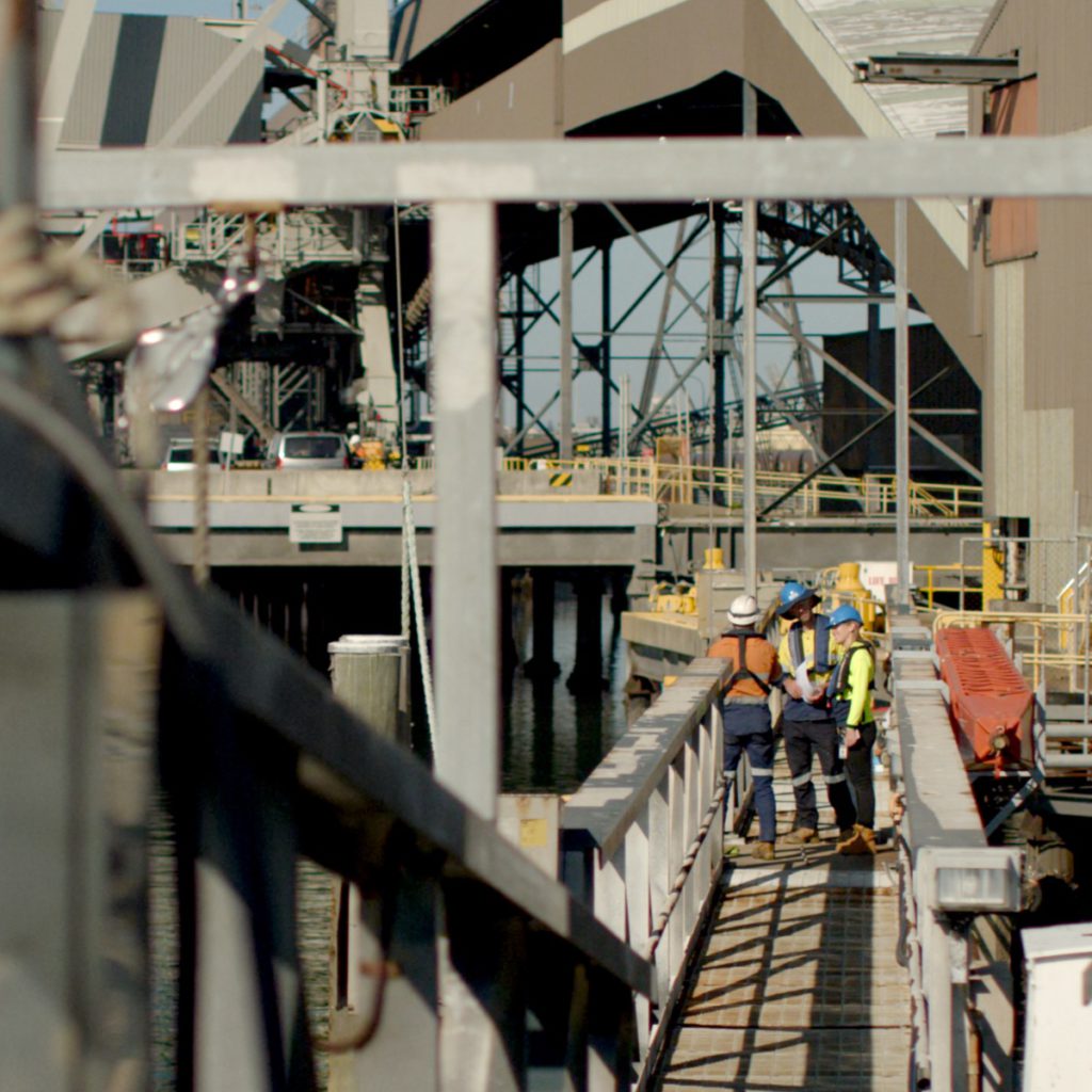 Construction workers in high vis standing on bridge at construction site.